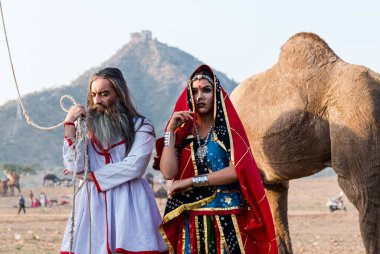 Puşkar, Rajasthan, Hindistan - Ekim 2019: Geleneksel Rajasthani ailesinin portre çekimi ve Pushkar Deve Fuarı 'nın arka planında develer