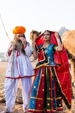 Puşkar, Rajasthan, Hindistan - Ekim 2019: Geleneksel Rajasthani ailesinin portre çekimi ve Pushkar Deve Fuarı 'nın arka planında develer