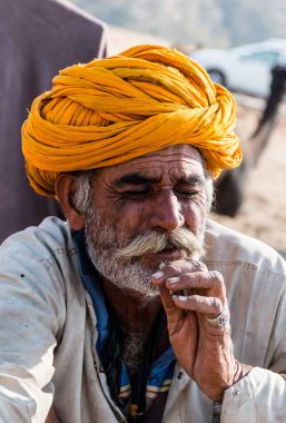 Puşkar, Rajasthan, Hindistan - Kasım 2019: Rajasthan 'lı Hintli erkekler fuar sırasında açık arazide sigara içiyorlar