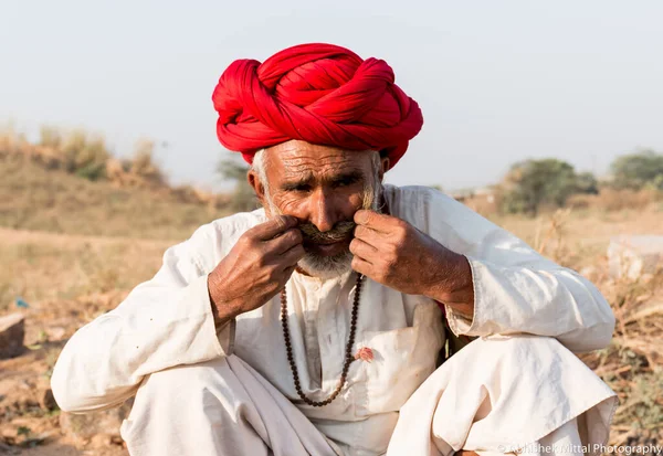 Puşkar, Rajasthan, Hindistan - Ekim 2017: Pushkar 'daki Deve Fuarında büyük bıyıklı Kırmızı Türbanlı Yaşlı Deve Taciri ve Beyaz Elbiseli