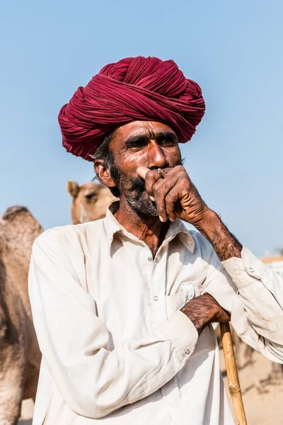 Puşkar, Rajasthan, Hindistan - Ekim 2017: Rajasthan 'lı Hintli adam fuar sırasında açık arazide sigara içiyor