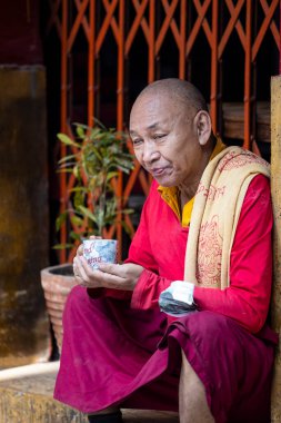 Yeni Delhi, Hindistan - Aralık 2021: Tibet manastırı bölgesinde kırmızı giysili Hint Tibet keşişi lama.