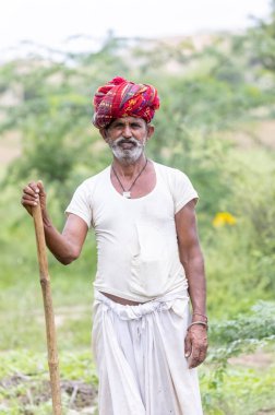 Jawai, Rajasthan, Hindistan - Eylül 2021: Jawai sahasında, ulusal başlık ve geleneksel beyaz elbise ve kırmızı sarıklı Rabari etnik grubunun yaşlı bir adamının portresi.