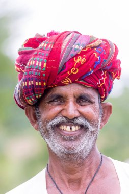 Jawai, Rajasthan, Hindistan - Eylül 2021: Jawai sahasında, ulusal başlık ve geleneksel beyaz elbise ve kırmızı sarıklı Rabari etnik grubunun yaşlı bir adamının portresi.