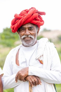 Jawai, Rajasthan, Hindistan - Eylül 2021: Jawai sahasında, ulusal başlık ve geleneksel beyaz elbise ve kırmızı sarıklı Rabari etnik grubunun yaşlı bir adamının portresi.