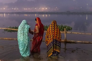 Ghaziabad, Uttar Pradesh, India - November 2021: Chhath Puja, Indian hindu devotees performing rituals of chhath puja in the night near river bank.
