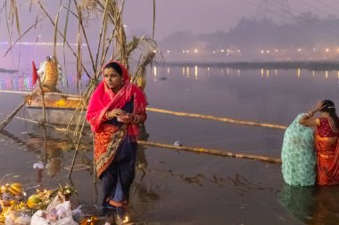 Ghaziabad, Uttar Pradesh, India - November 2021: Chhath Puja, Indian hindu devotees performing rituals of chhath puja in the night near river bank. clipart