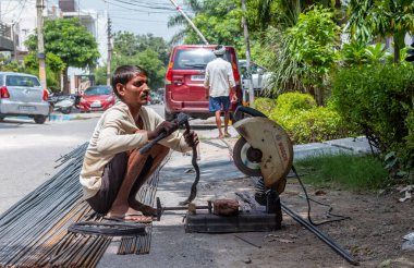 Gaziabad, Uttar Pradesh, Hindistan - Ekim 2021: Lanter inşaatı için demir açı öğütücüsüyle yeni inşaat alanında veya garajda çalışan tanımlanamayan erkek işçi. 