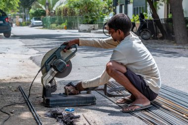 Gaziabad, Uttar Pradesh, Hindistan - Ekim 2021: Lanter inşaatı için demir açı öğütücüsüyle yeni inşaat alanında veya garajda çalışan tanımlanamayan erkek işçi. 