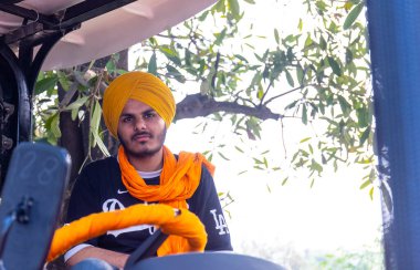 Anandpur Sahib, Punjab, Hindistan - Mart 2022: Holi festivalinde Hola Mohalla 'nın Anandpur Sahib kutlamaları sırasında traktörde oturan erkekler.