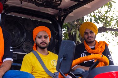 Anandpur Sahib, Punjab, Hindistan - Mart 2022: Holi festivalinde Hola Mohalla 'nın Anandpur Sahib kutlamaları sırasında traktörde oturan erkekler.