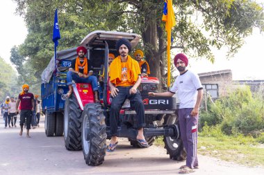Anandpur Sahib, Punjab, Hindistan - Mart 2022: Holi festivalinde Hola Mohalla 'nın Anandpur Sahib kutlamaları sırasında traktörde oturan erkekler.