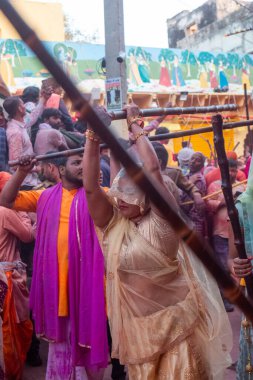Barsana, Uttar Pradesh, Hindistan - Mart 2022: Barsana 'lı Hindu kadınlar ellerinde peçeleri ve bambu çubuklarıyla erkek insanları Nandgaon' dan geleneksel lathmar holi ritüeli olarak yeniyorlar.