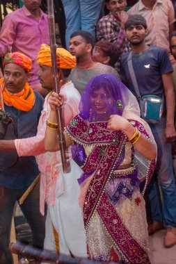 Barsana, Uttar Pradesh, Hindistan - Mart 2022: Barsana 'lı Hindu kadınlar ellerinde peçeleri ve bambu çubuklarıyla erkek insanları Nandgaon' dan geleneksel lathmar holi ritüeli olarak yeniyorlar.