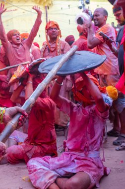 Barsana, Uttar Pradesh, Hindistan - Mart 2022: Barsana 'lı Hindu kadınlar ellerinde peçeleri ve bambu çubuklarıyla erkek insanları Nandgaon' dan geleneksel lathmar holi ritüeli olarak yeniyorlar.