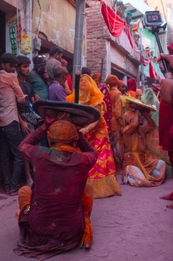 Barsana, Uttar Pradesh, Hindistan - Mart 2022: Barsana 'lı Hindu kadınlar ellerinde peçeleri ve bambu çubuklarıyla erkek insanları Nandgaon' dan geleneksel lathmar holi ritüeli olarak yeniyorlar.