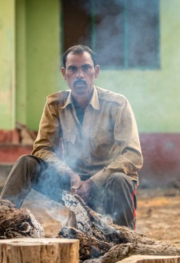 Şenlik ateşinin yanında oturan Hintli adam