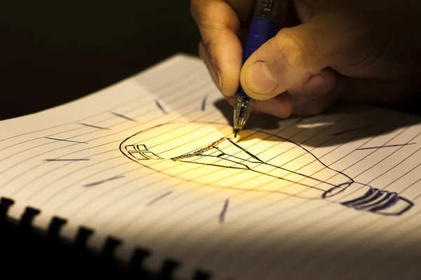 Concept of idea: writing a light bulb in a copybook — Stock Photo, Image