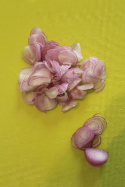 Dilimlenmiş arpacık soğanı (kırmızı soğan) yeşil kesim tahtasında.