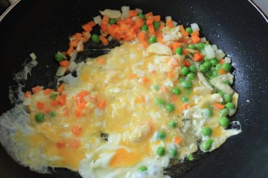 Küçük parça beyaz soğan, sarımsak, havuç, taze bezelye ve yumurta haşlanmış yağ tavasında omlet ya da pilav pişirirken. Asya besin maddeleri.