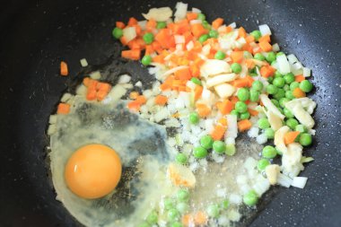 Kızarmış pirinç pişirirken küçük parça beyaz soğan, sarımsak, havuç, bezelye ve yumurta. Asya besin maddeleri.