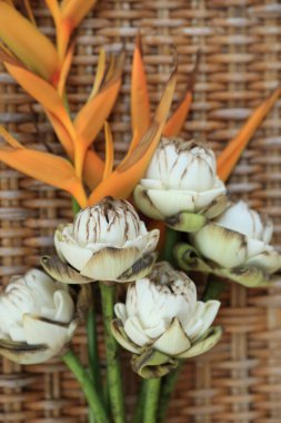 Kurumuş çiçek buketi (beyaz Lotus ve sarı Heliconia) klasik örgü arka planında. 