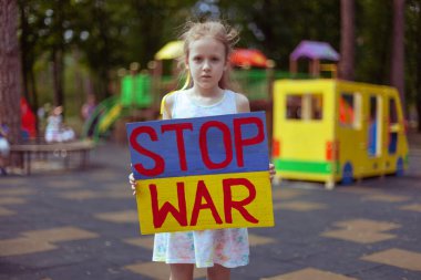 Ukrainian girl child asks to stop the war. In her hands board stop war.