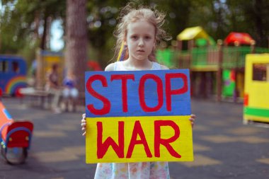 Ukrainian girl child asks to stop the war. In her hands board stop war.