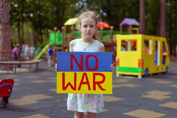 Ukrainian girl child asks to stop the war. In her hands board no war.