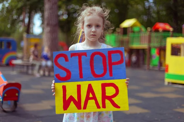 Ukrainian girl child asks to stop the war. In her hands board stop war.