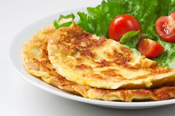 Omelet met cherry tomaten en groene salade op wit bord — Stockfoto