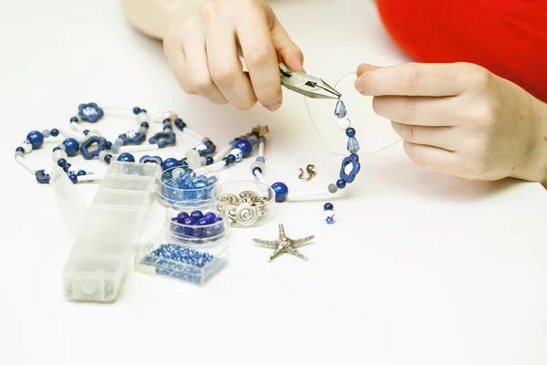Жінка робить намисто з різнокольорових пластикових намистин — стокове фото