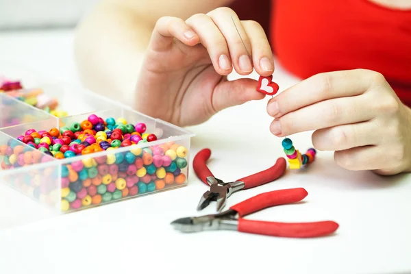 Vrouw maken ketting van kleurrijke Kunststof kralen — Stockfoto