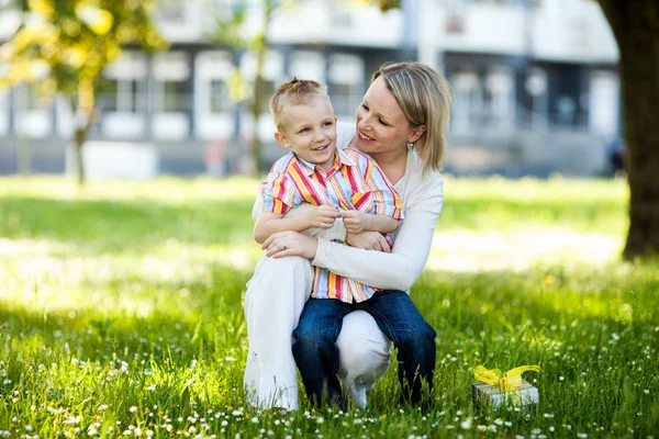 Schöner Junge und Mutter im Frühling mit Geschenk. Konzept zum Muttertag oder Geburtstag — Stockfoto