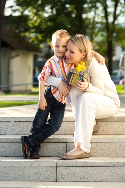 Bellissimo ragazzo e mamma in primavera con regalo. Concetto di festa della mamma o del compleanno — Foto Stock