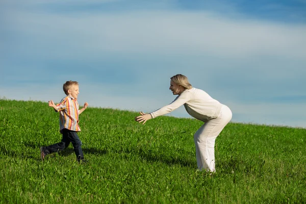 Schöner Junge und Mutter spielen im Frühlingspark. Glückliches Familienkonzept. — Stockfoto