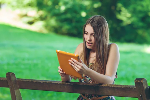 güzel bir genç kadın tablet ile parkta bankta oturmuş