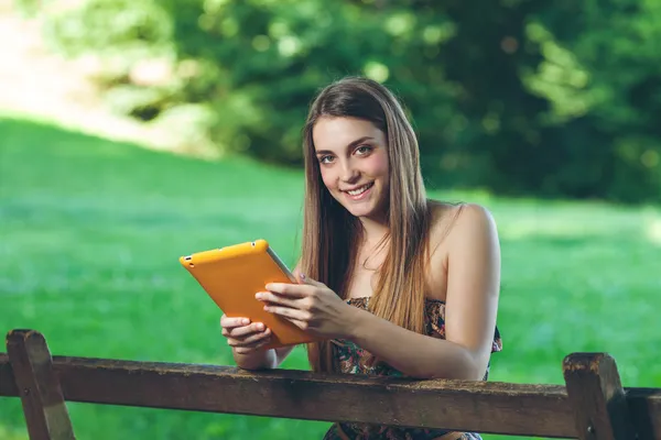 Красивая молодая женщина сидит на скамейке в парке с табличкой — стоковое фото