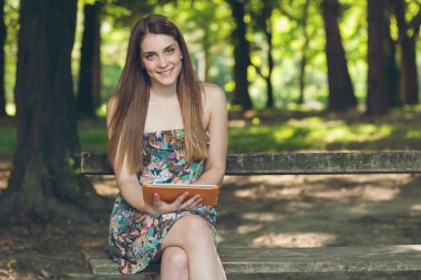 tablet ile parkta oturan güzel genç kadın