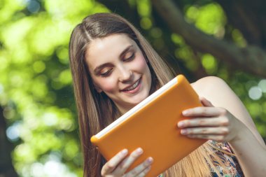 tablet ile parkta oturan güzel genç kadın