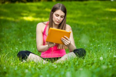 tablet ile parkta oturan güzel genç kadın