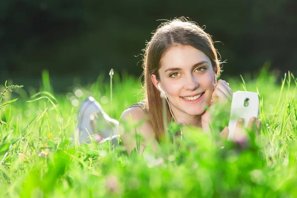Parkta güzel bir genç kadın akıllı telefon üzerinde müzik dinle — Stok fotoğraf