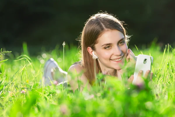 Gyönyörű fiatal nő parkban hallgatni a zenét, a szúró telefon — Stock Fotó