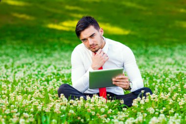 bilgisayar tablet tutan şehir parkında oturan genç iş adamı