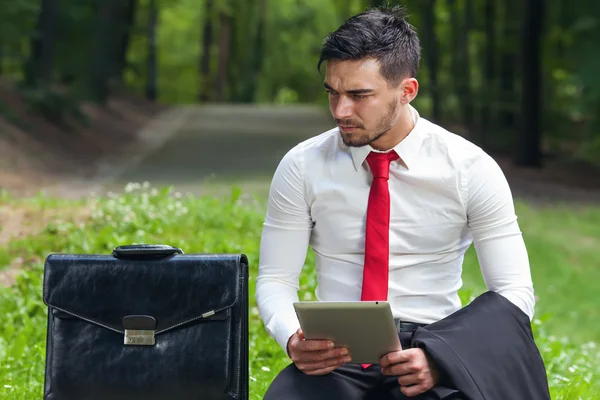 bilgisayar tablet tutan şehir parkında oturan genç iş adamı