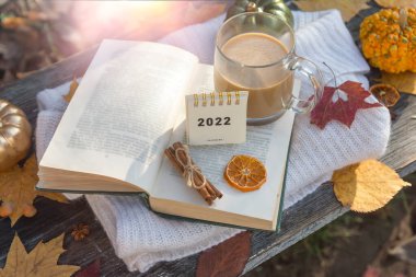 Bir sonbahar gününün arka planında 2022 için takvim. Kahve, kitap, balkabağı, cadılar bayramı.