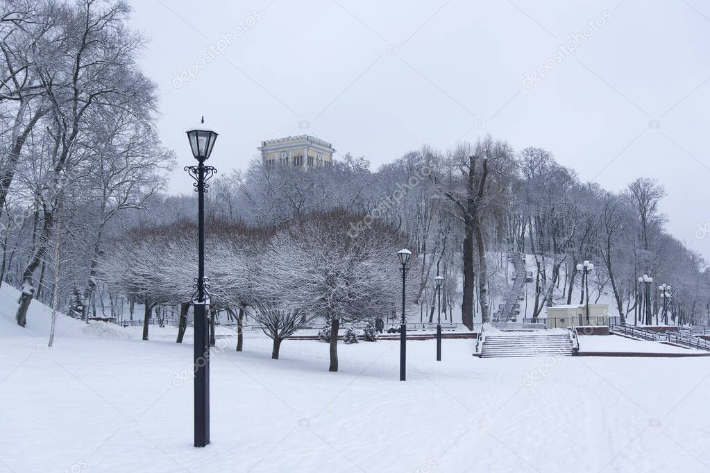 View of the snow-covered park in winter, snow-covered trees, bushes, and a bridge, Gomel, Belarus.
