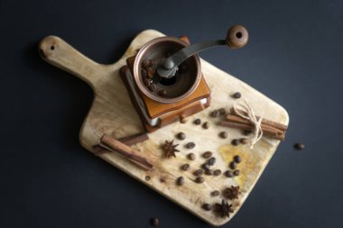 Kahve öğütücüsü, kalp şeklinde kahve çekirdekleri ve ahşap bir yüzeyde tarçın. 2022 yılı için bir fincan aromatik kahve ve taze çörekler..