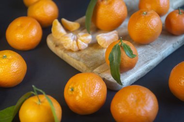 Koyu bir arka planda ve odanın içinde parlak olgun mandalinalar..