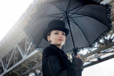 19. yüzyılın katı siyah giysileri içindeki gizemli güzel bayan eski karanlık kalenin karanlığına şüpheli bir şekilde bakıyor. 19. yüzyıl - 20. yüzyıl başları tarzı. Korku, gerilim.